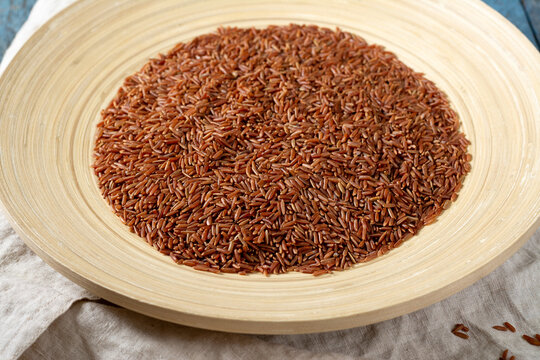 Red rice in a large wooden plate on a blue wooden table. Rustic style	