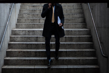 black man in a suit walks down a subway stairs while talking on the phone