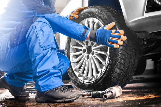 Man mechanic with car tire in service center.