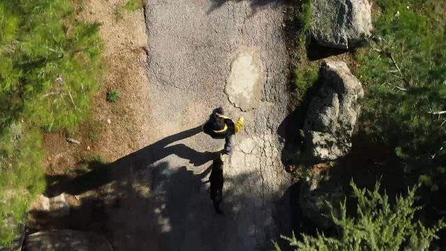 Aerial shot of a boy walking with a dog in nature seen from the drone. Walk down a path