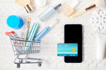 winter flat lay with credit card, cosmetics and snowflake