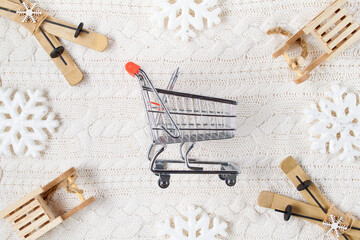 Fototapeta na wymiar winter flat lay with snowflakes, sleds, skis and shopping cart
