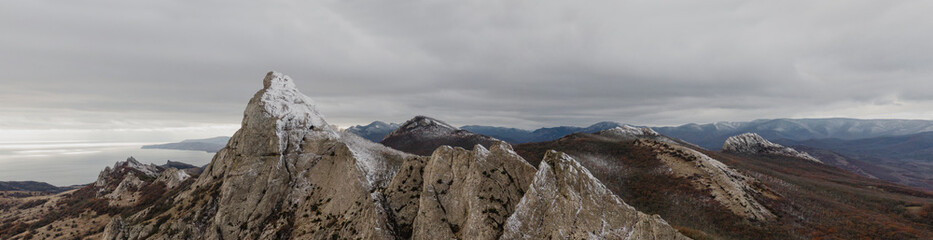 Panorama of mountain peaks in the snow with mountainous terrain sea and sky in the background....