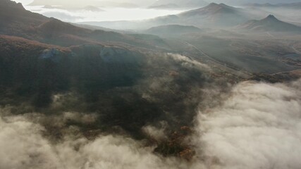 Fog covers sunset valley with mountains at the end of the day Aerial shot of smooth flight over the half-wild panorama