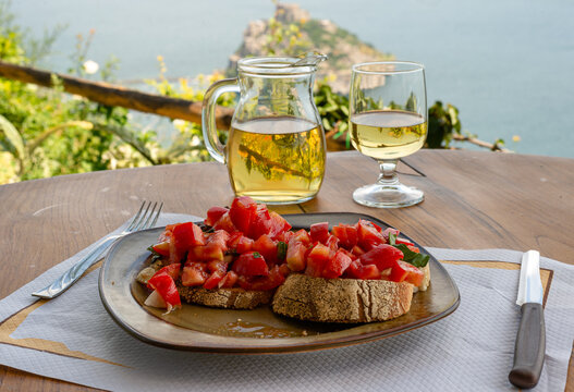 Italian bruschetta and white wine against the background of the Aragonese castle, Ischia island, Italy