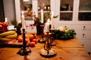 Low light. tangerines and apples in a metal basket and burning candles