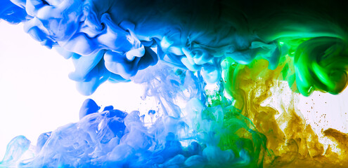 Flowing blue, green and yellow ink in water. Abstract colorful background