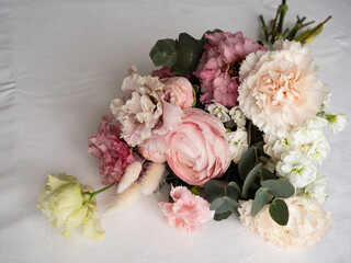 Fresh delicate flowers pink lisianthus, cream dianthus and eucalyptus on a white background in the morning light