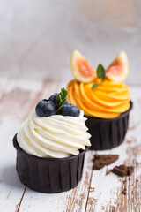 Cupcakes or muffins with white cream and berries. Cake celebration, delicious dessert, close-up