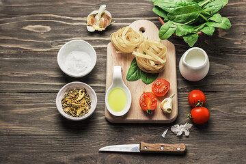 Italian food or ingredients background with fresh vegetables, pasta, spinach and spices. Vegan or gluten-free diet. Copy space. Wooden dark background.