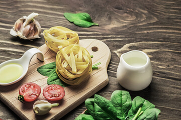 Italian food or ingredients background with fresh vegetables, pasta, spinach and spices. Vegan or gluten-free diet. Copy space. Wooden dark background.