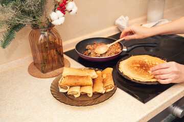Cooking homemade Russian pancakes Bliny with meat on Shrovetide - Maslenitsa. Woman cooks pancakes in her kitchen