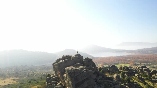 Aerial shot of boy on rocks with drone in a natural park with swamp in autumn