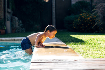 Little boy striving for get out of a swimming pool. Child learning to swim.
