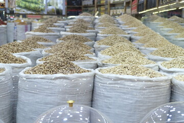 Broken and unbroken pistachios stand side by side in sacks in the shop