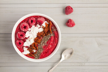Top view of smoothies bowl with raspberries and natural superfoods on the gray background