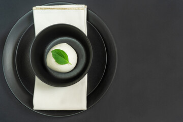 mozzarella in a black bowl and black plate on dark table