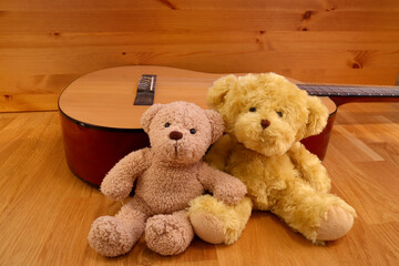 Two cute stuffed teddy bears. Leaning against a real guitar. Softly smiling kindly. 