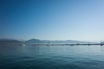 Seascape with calm blue water, yachts and mountains on horizon in Fethiye bay, Turkey. Sunny day perfect blue sky
