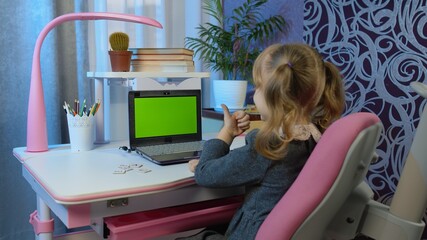 Child girl studying homework on laptop webcam online lesson at home. Chroma key pc green screen....