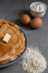Homemade crepes with ingredients: flour, eggs. Pancakes on the grey background