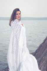 Fototapeta na wymiar brunette woman in white long dress standing by the water