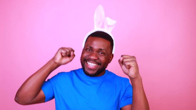 man wearing cute easter bunny ears in studio pink wall background