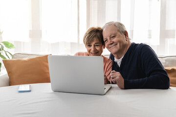 Hispanic senior couple making video call with family inside home during lockdown isolation - Joyful elderly lifestyle and technology concept - Focus on woman face