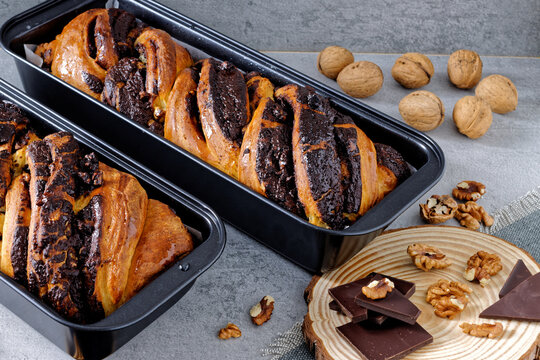 Krantz cake with chocolate and nuts filling in black baking tin mold. Yeast-risen dough twisted cake.