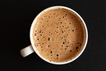Cup of coffee with foam on black background
