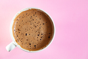 Cup of coffee with foam on pink background