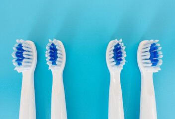 Four toothbrushes close-up looking in different directions on a blue background, top view