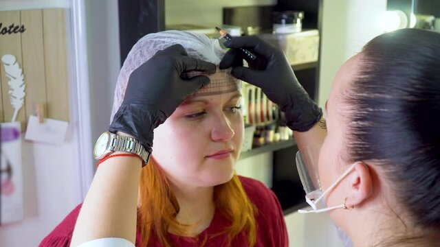 Make-up artist marks up client eyebrows in front of permanent makeup. Professional correction procedure of female eyebrows in beauty salon.