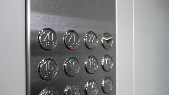 A female hand presses the elevator button. Selection of the 21th floor in a new metal elevator.