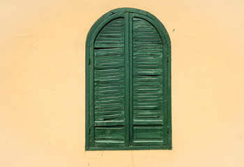 Wall with window with closed green blinds