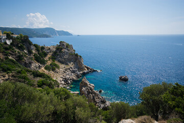 View on the bright blue azure sea and rocks and green trees and blue sky from the mountain at in Corfu island Greece