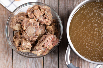 Saucepan with bone broth meat and vegetables cooking ingredients and spices on the kitchen table. Top view
