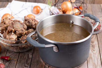 Bone Broth Bouillon in Metal saucepan on the wooden table, paleo diet