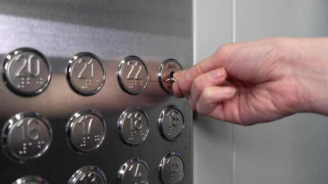 A female hand presses a button in the elevator. The girl turns on and off the ventilation in a modern metal elevator.