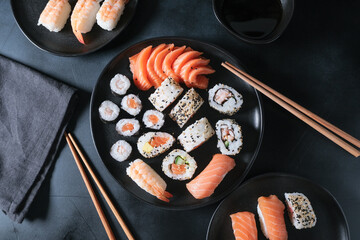Lunch or dinner at a Japanese restaurant. Set  sushi maki rolls  with salmon, avocado, cream cheese. Sushi menu. Japanese food. Black background. Top view. Food delivery coronavirus