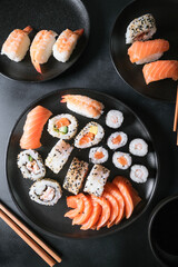 Lunch or dinner at a Japanese restaurant. Set  sushi maki rolls  with salmon, avocado, cream cheese. Sushi menu. Japanese food. Black background. Top view. Food delivery coronavirus