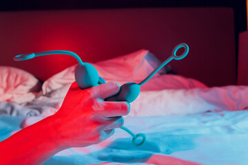 Woman holding anal balls in bed close-up.