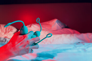 Woman holding anal balls in bed close-up.