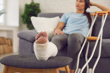 Concept of rehabilitation of people after physical injury. Young woman with broken leg in plaster...