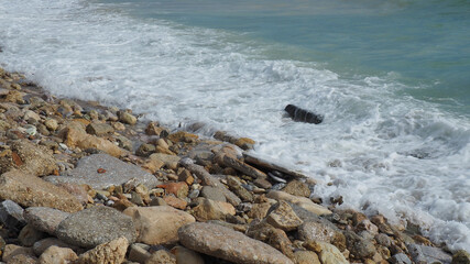 Mediterranean rocky beach with wavy sea in a cloudy morning
