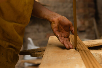 Craftsman hand arranging long thin clay tubes. Shallow depth of field