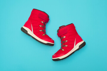 Kids or teenage pink winter boots isolated on blue background. Winter boots for girls