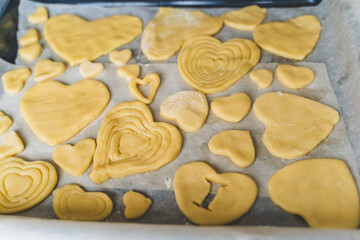 Little girls, sisters cooking homemade heart shaped cookies for valentine's day. Holiday for all lovers. Gift, surprize for mom. Red molds, rolling pin, flour, dough.Handmade family, bakery with kids
