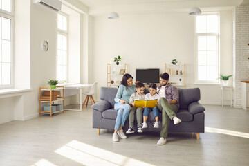Happy people sitting together on sofa in modern interior of new house or studio apartment. Family...