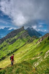 Men hikes trail next to the cliff in the swiss nature and mountain region of Speer, Federispitz, Chuemettler, Grappehorn